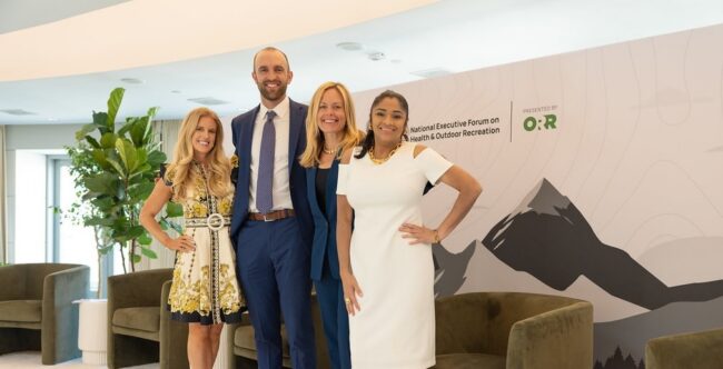 ORR_Team_Photo Three women and one man stand on a stage in business professional attire. The backdrop reads, "ORR."
