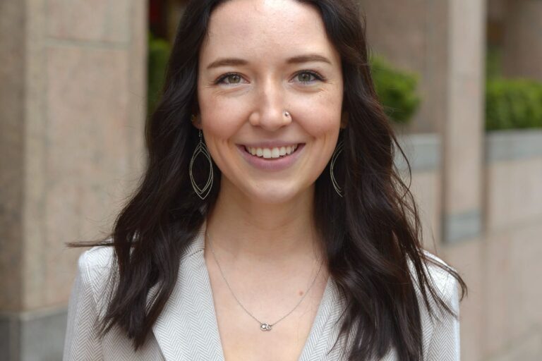68d2aaa44b0c75f742e64a36_ftf25-Team-Headshots-TaylorAnnWooley Woman smiling with gray blazer