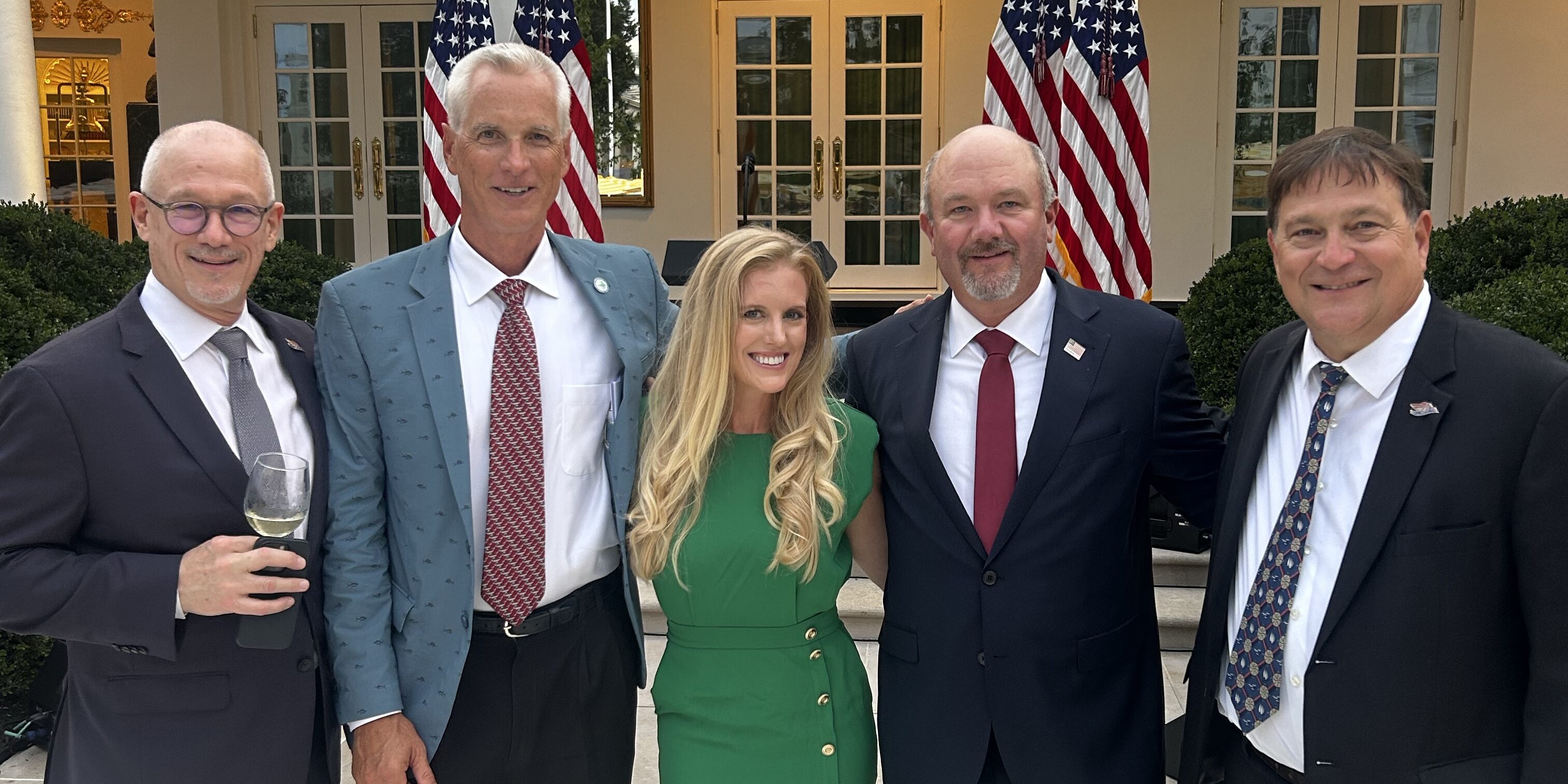 Five people in suits pose outside of the Oval Office in Washington, D.C.