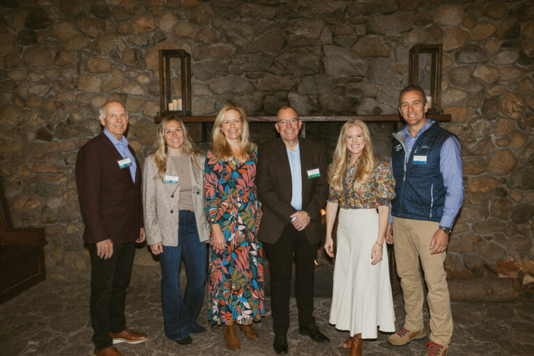 Six professionals, including members of the Administration, stand in front of a fire place in Valhalla Tahoe.